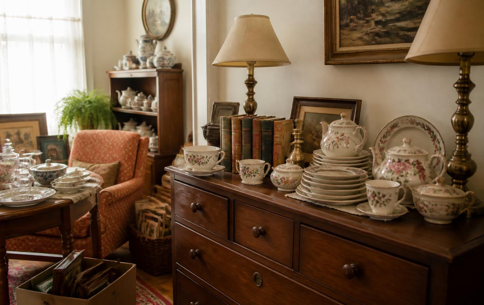 Muebles de madera, porcelana y lámparas de bronce dentro de una casa durante una estate sale